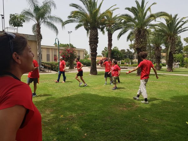 5 אנשים מסתובבים בחולצות אדומות על דשא ירוק יום ספורט של קלאבהאוס
