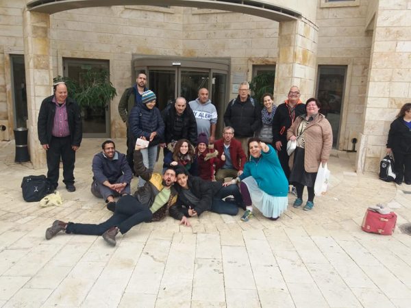 תמונה קבוציתי בכניסה לאכסניה-15 אנשים עומדים ויושבים - טיול לעכו ברכבת קלאבהאוס ירושלים