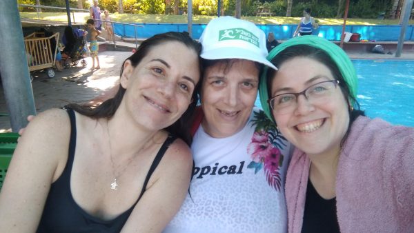 שלוש נשים מחייכות למצלמה ומאחוריהן בריכת שחייה קלאבהאוס ירושלים