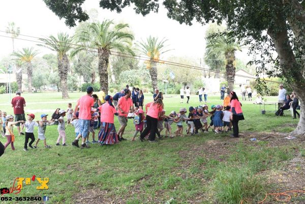 קבוצה של אנשים מושכת בחבל ברקע עצים ודשא קלאבהאוש יום ספורט