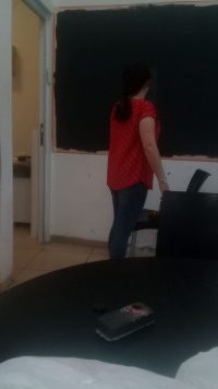 אישה עם חולצה אדומה צובעת בלבן קיר ביחידה המשרדית של קלאבהאוס ירושלים.